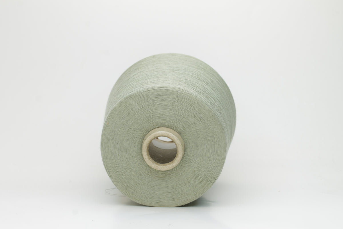 A finely spun, lustrous two-ply cotton yarn in a muted, earthy soft sage green, showcasing a gentle twist and smooth finish.