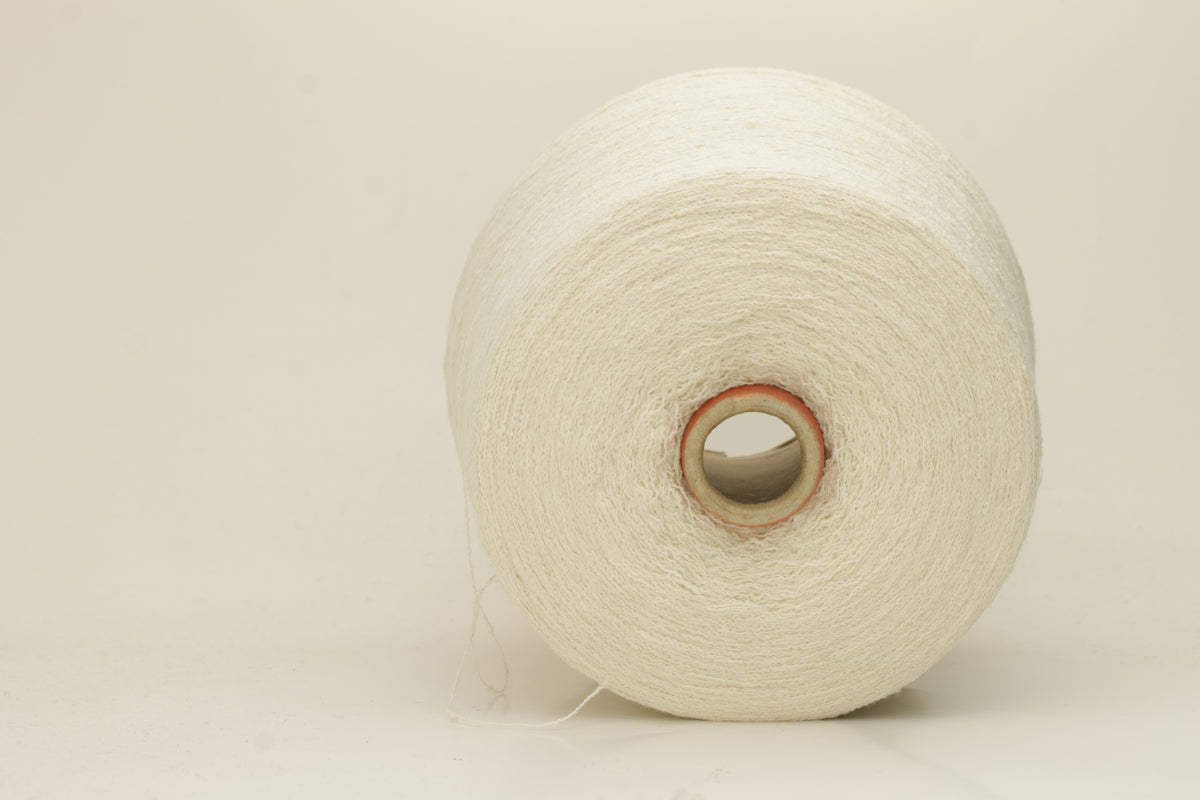 Close-up of a pure white, textured Nodino yarn, showing subtle, irregular nubs and a soft, matte sheen; twisted ply visible.
