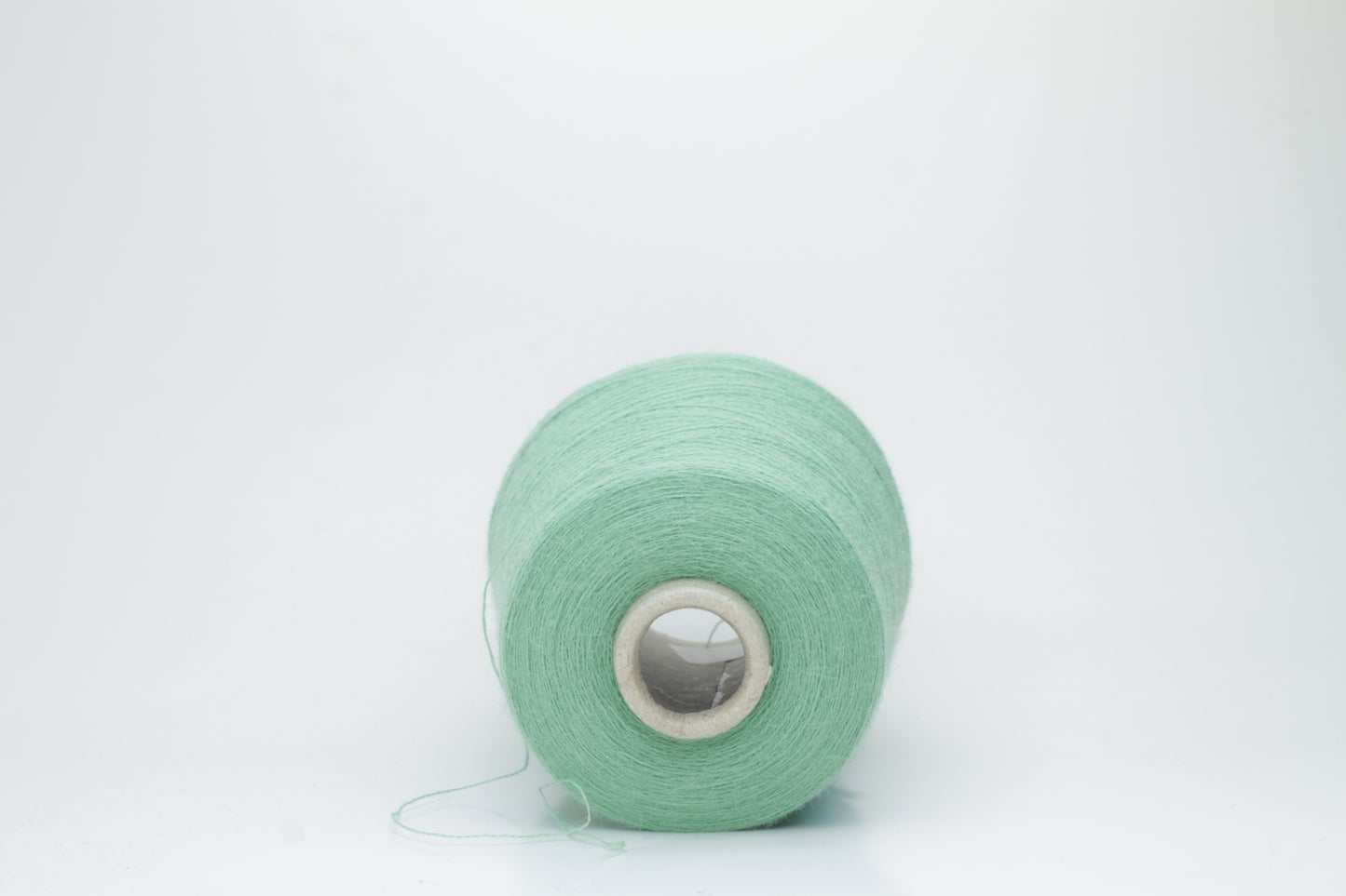 Close-up of a skein of soft, plied alpaca merino yarn in a deep green, showing subtle sheen and fine fiber halo.