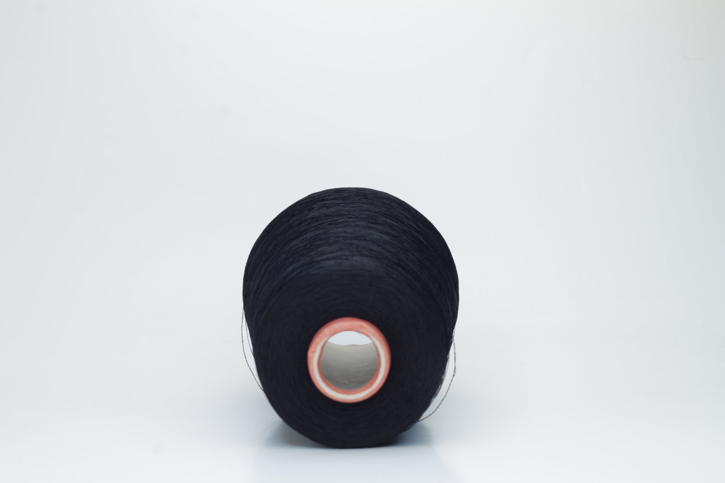 A single, tightly spun strand of incredibly fine, jet black silk yarn, showcasing a brilliant, almost glass-like sheen.