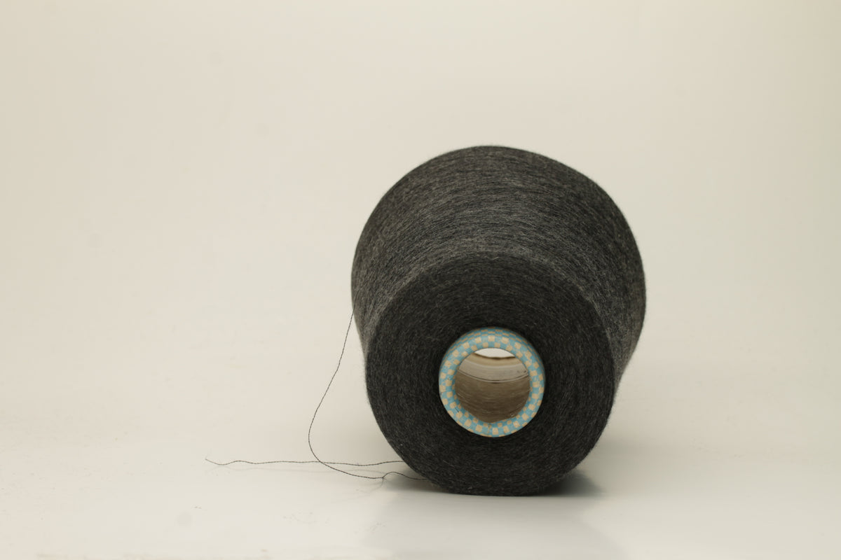Close-up of a luxurious, finely spun two-ply cashmere silk blend yarn in a soft, elegant gray shade with a subtle sheen, showcasing its delicate texture.