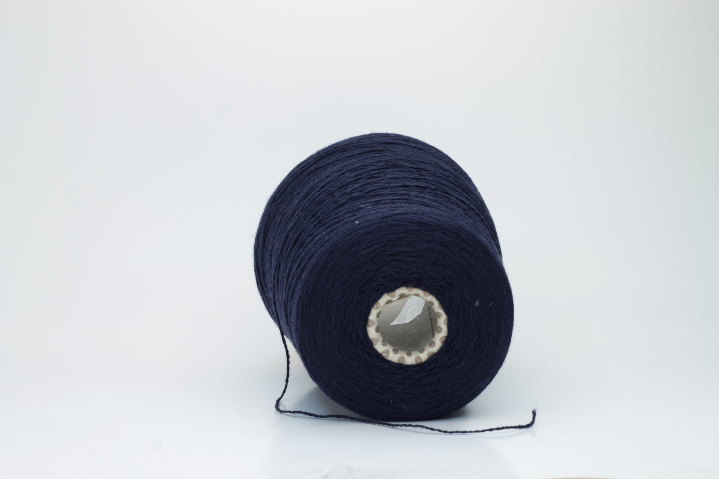 A tightly spun two-ply yarn, rich navy blue, made from exceptionally soft, fine cashmere fibers with a slight halo, presented as a graceful hank.