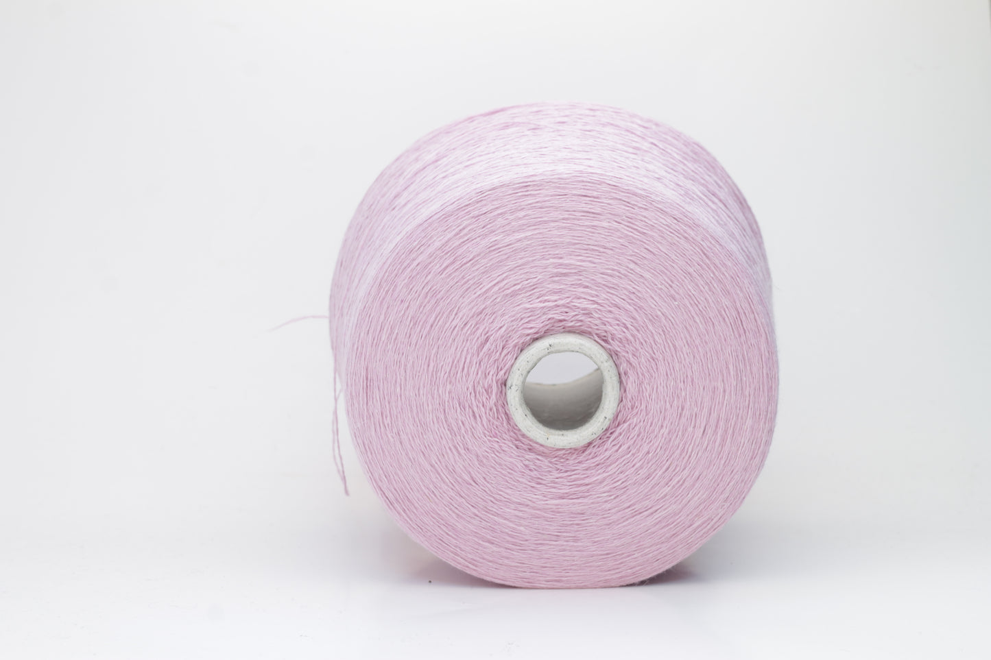 A soft, plump 2-ply yarn in a delicate antique rose hue, loosely coiled, exhibiting a subtle, silken sheen and slight halo. The fibers appear evenly spun.
