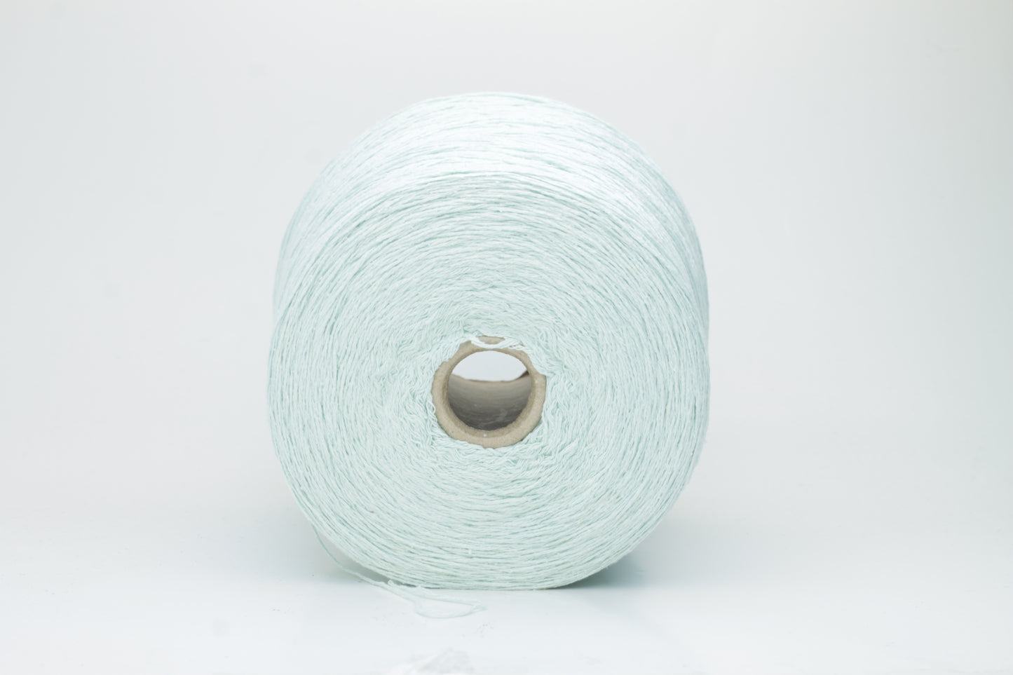 Close-up of a skein of unspun, single-ply bourette silk yarn. It has a natural, slightly textured, slubbed surface with a soft matte sheen in a serene acqua blue-green hue.