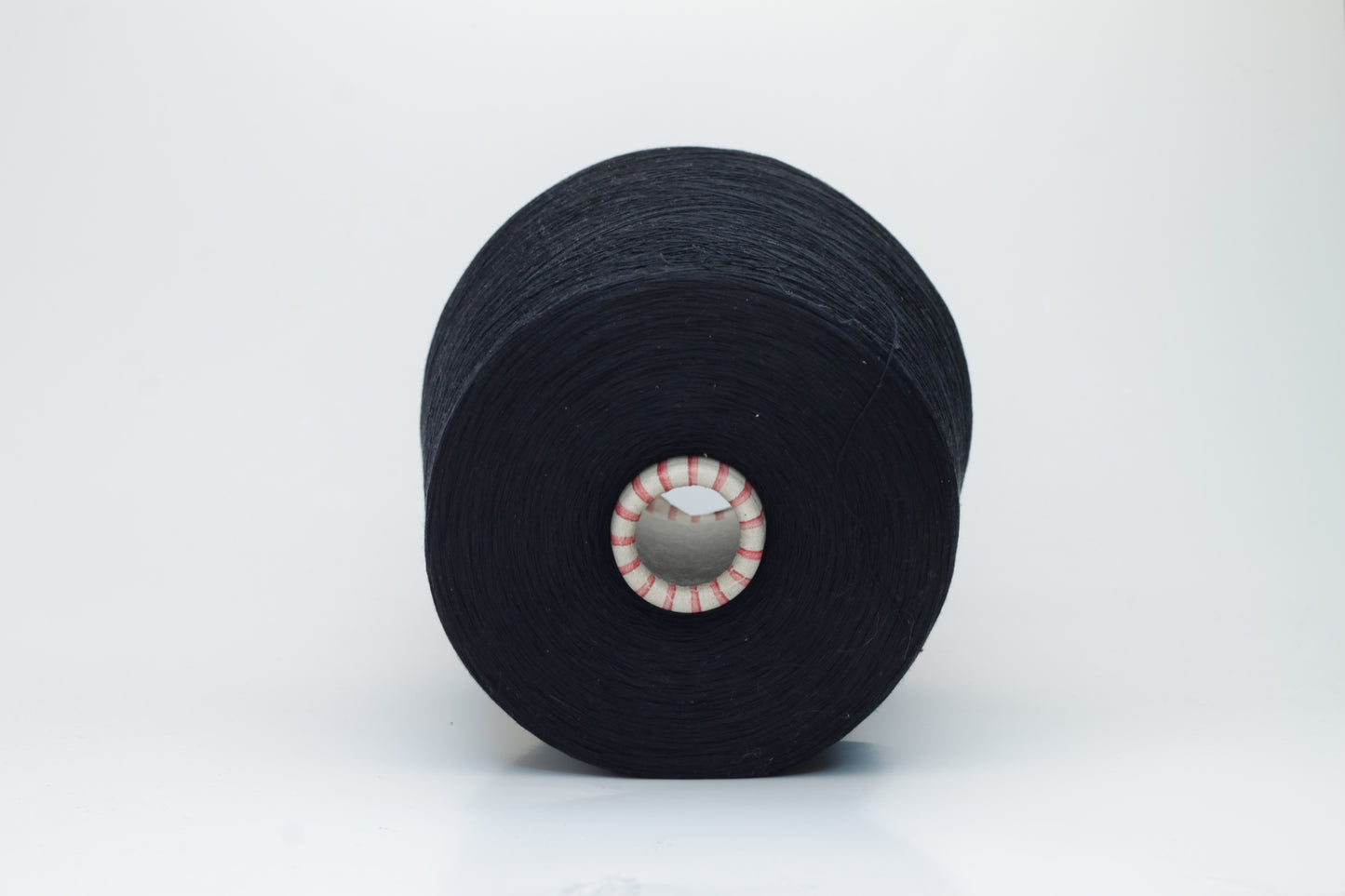 Close-up of luxurious black 100% silk yarn, tightly plied with a smooth, high-luster surface reflecting light. It has a deep, true black color, wound evenly on a cone.