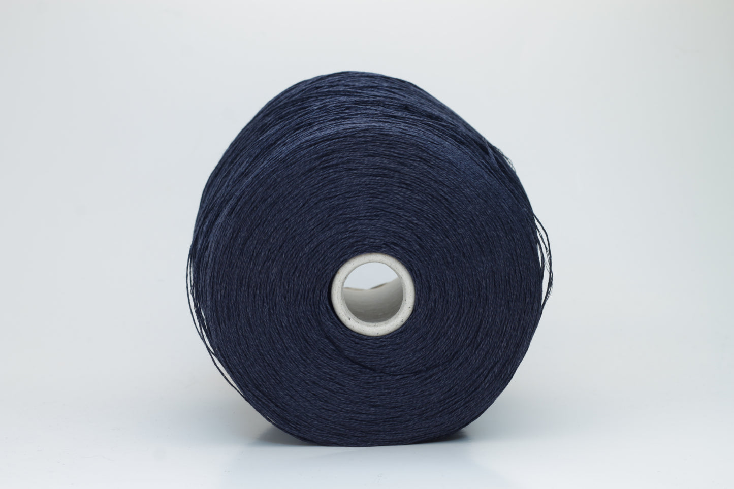 Close-up of pristine Navy linen and viscose blend yarn, softly twisted with a subtle sheen, showcasing its fine, smooth texture.