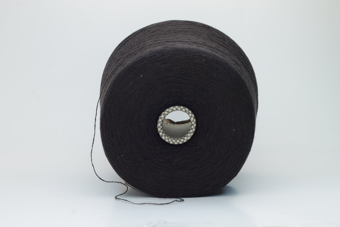 Close-up of a two-ply dark brown cashmere yarn, softly twisted with a subtle sheen, displaying its deep rich hue and delicate fuzziness, ready for luxury crafting.