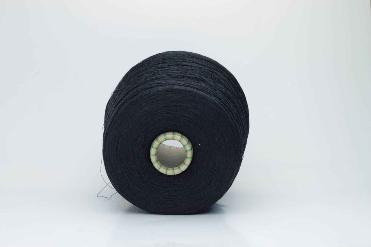 Spool of rich, deep black silk yarn, showcasing its fine, smooth plies and radiant, natural luster against a soft background.
