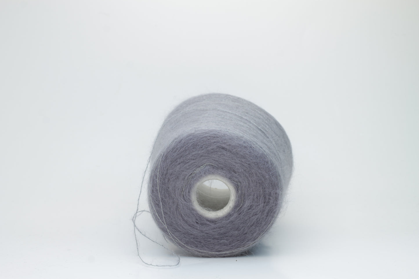 Close-up of fluffy Smog (Gray) kid mohair and silk blend yarn, subtly lustrous with a soft halo, gently twisted into a fine, delicate thread.