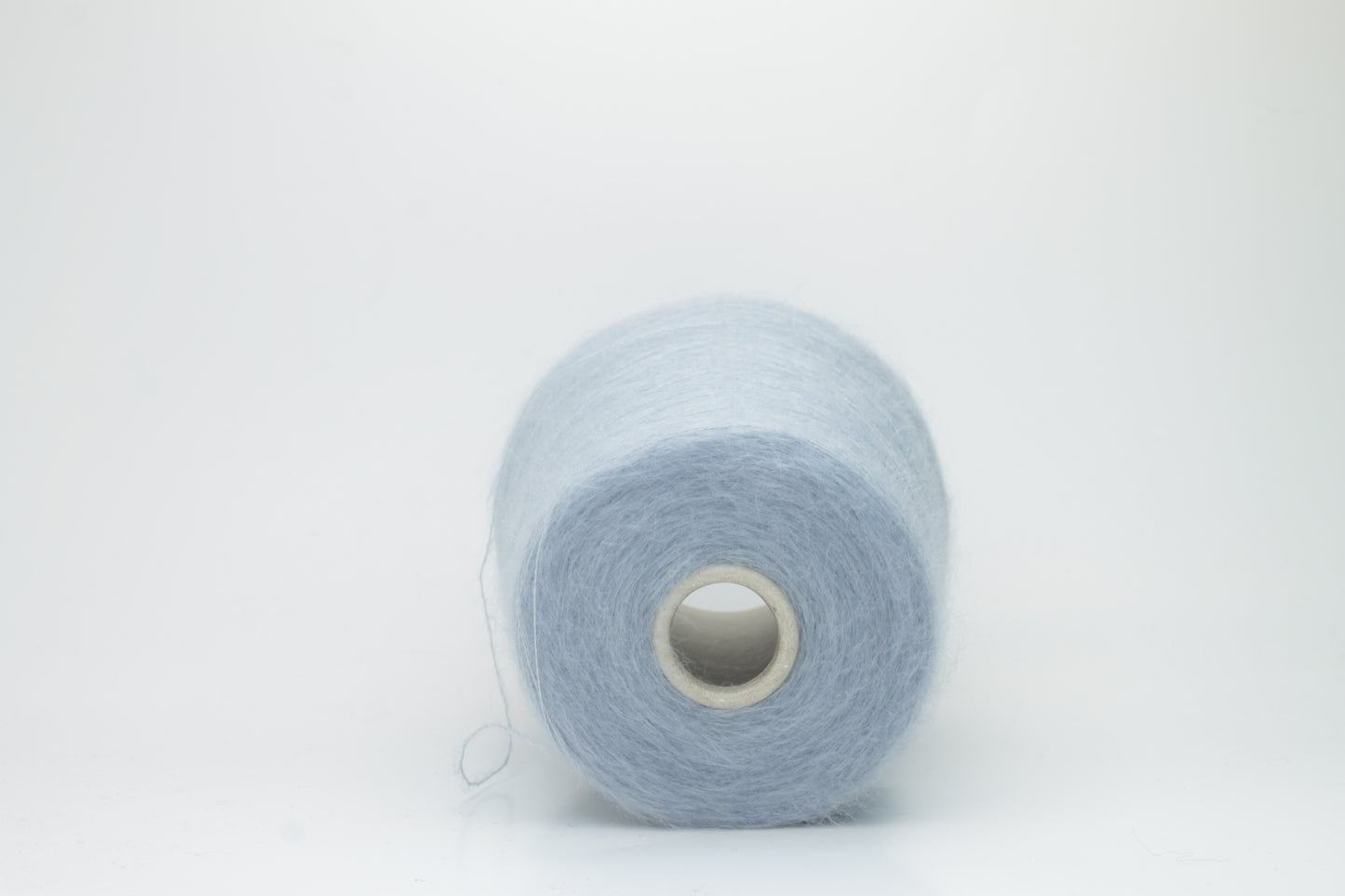 Close-up of fluffy Cielo kid mohair and silk blend yarn, subtly lustrous with a soft halo, gently twisted into a fine, delicate thread.