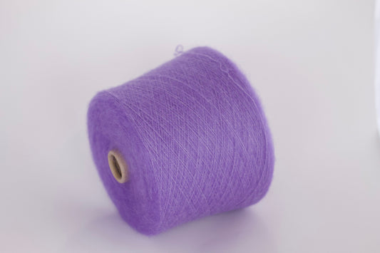 Close-up photograph of a cone of medium purple kid mohair and silk yarn, showcasing the fluffy fibers and subtle sheen. The ply twist is visible, creating a delicate thread structure with moderate fluffiness.