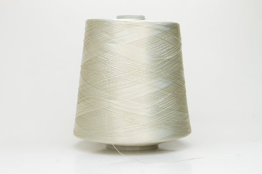 Close-up of finely plied natural silk yarn in a pale, warm champagne tone, reflecting light with a soft, radiant shimmer.
