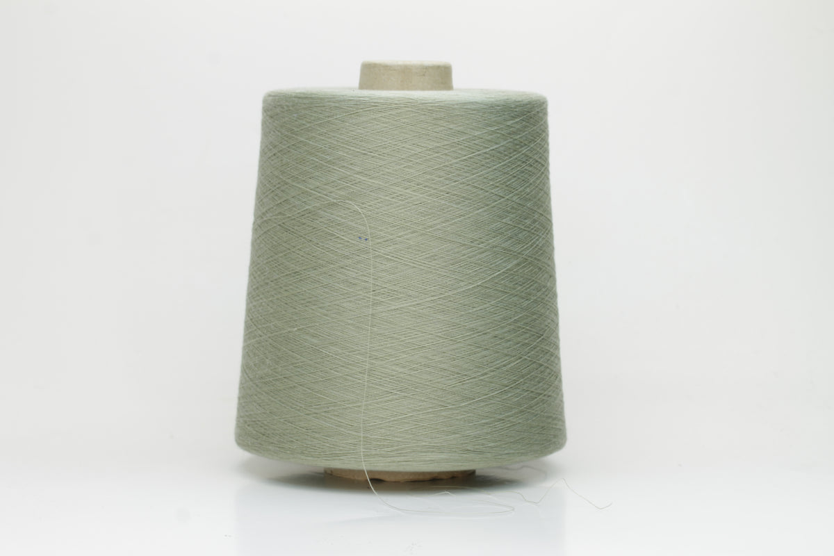 A finely spun, lustrous two-ply cotton yarn in a muted, earthy soft sage green, showcasing a gentle twist and smooth finish.