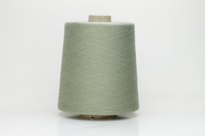 A finely spun, lustrous two-ply cotton yarn in a muted, earthy soft sage green, showcasing a gentle twist and smooth finish.