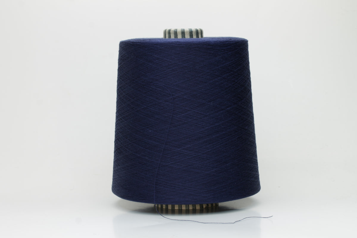 Close-up of a meticulously twisted, fine-gauge cotton yarn in a deep, lustrous classic navy blue with a subtle sheen.