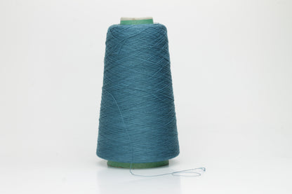 A skein of luxurious 100% pure silk yarn in a deep, shimmering petrol blue, displaying a smooth, finely spun single ply with a high, lustrous sheen.
