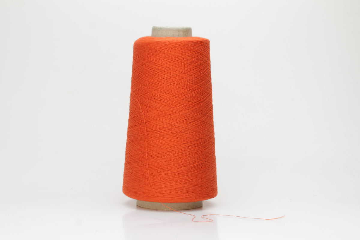 Close-up of a vibrant Mandarin Orange cotton yarn cone, revealing its smooth, tightly twisted single ply and subtle natural sheen.