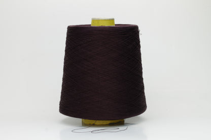 Close-up of a tightly wound cone of smooth, fine cotton yarn in a rich, deep eggplant color, showing a subtle sheen and even 3-ply twist.