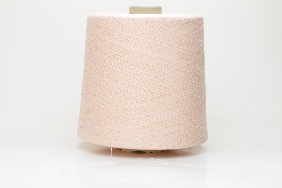 Close-up of finely spun, delicate powder pink cotton yarn, showcasing its soft, matte finish and subtle, even twist with excellent stitch definition.
