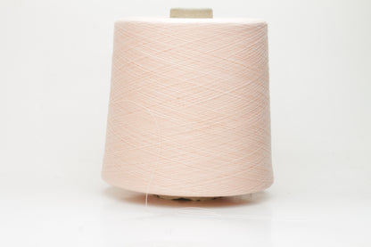 Close-up of finely spun, delicate powder pink cotton yarn, showcasing its soft, matte finish and subtle, even twist with excellent stitch definition.