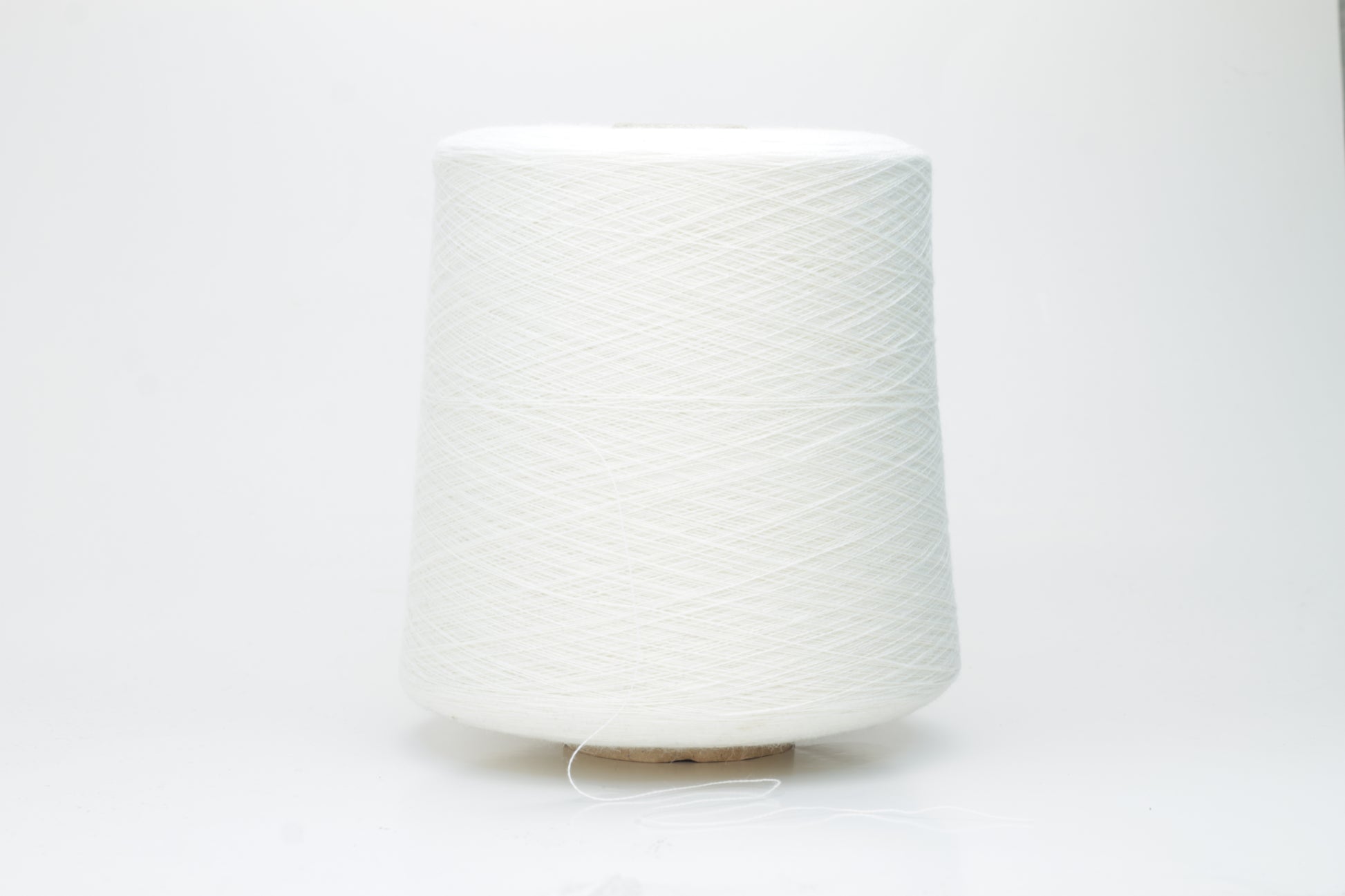 Close-up view of a creamy white, fluffy yarn strand with subtle sheen. The yarn shows a twisted ply construction and a dense, luxurious texture, hinting at its high cotton and cashmere fiber content.