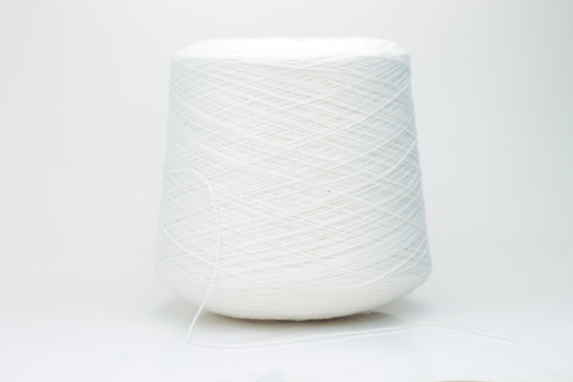 Close-up of a pure white cashmere yarn skein, showcasing its soft, slightly fluffy texture and subtle sheen with a gently twisted, fine two-ply structure.