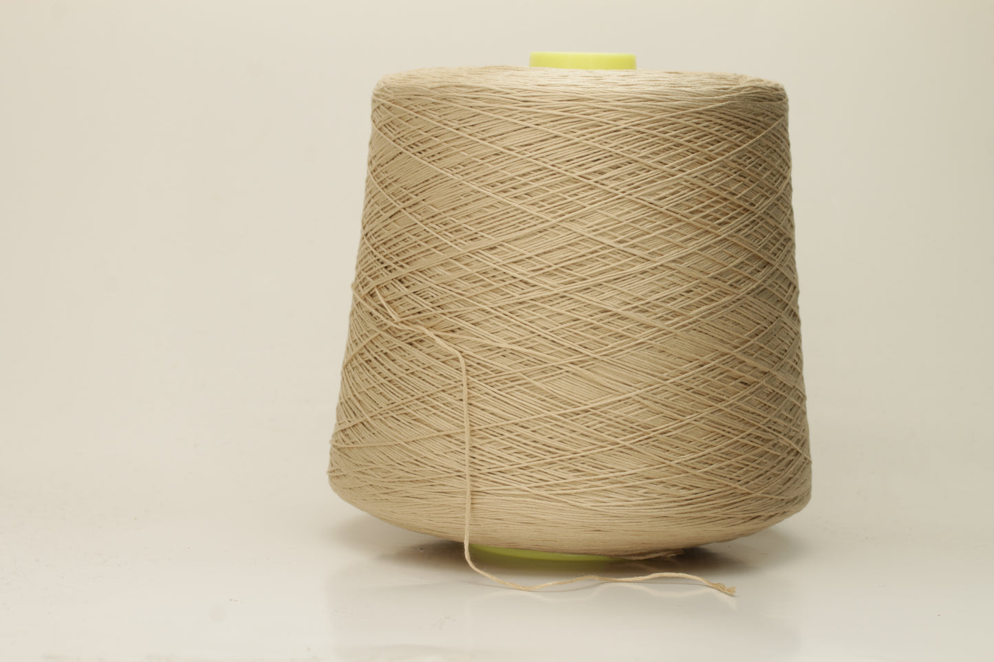 Close-up of a single strand of lustrous, fine-gauge beige silk and cotton yarn, showcasing its smooth, even twist and soft sheen.