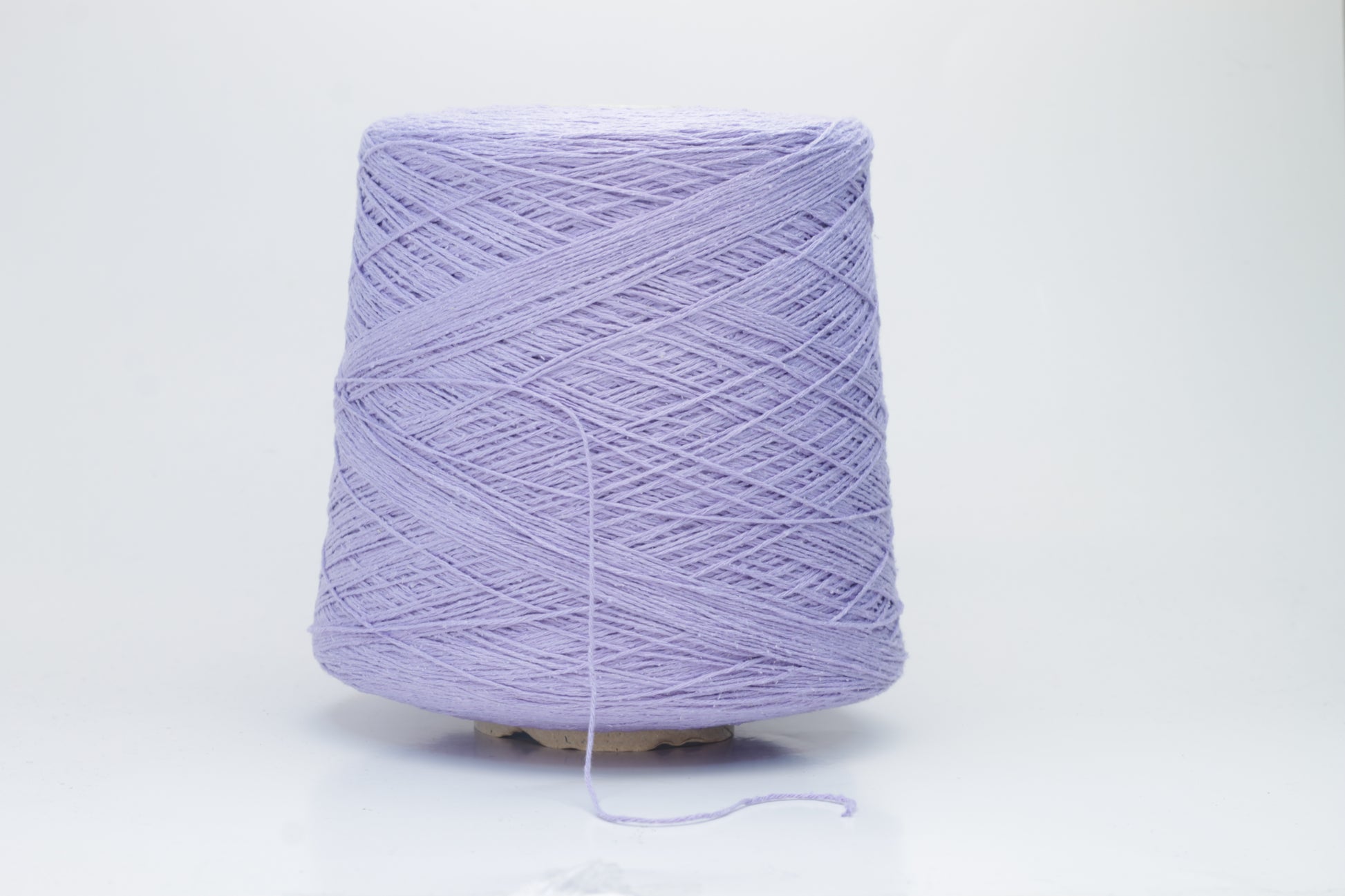 Close-up of a single strand of matte lavender silk bourette yarn, showcasing its natural slub texture and soft, nubbly appearance, coiled gently.