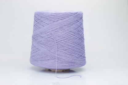 Close-up of a single strand of matte lavender silk bourette yarn, showcasing its natural slub texture and soft, nubbly appearance, coiled gently.
