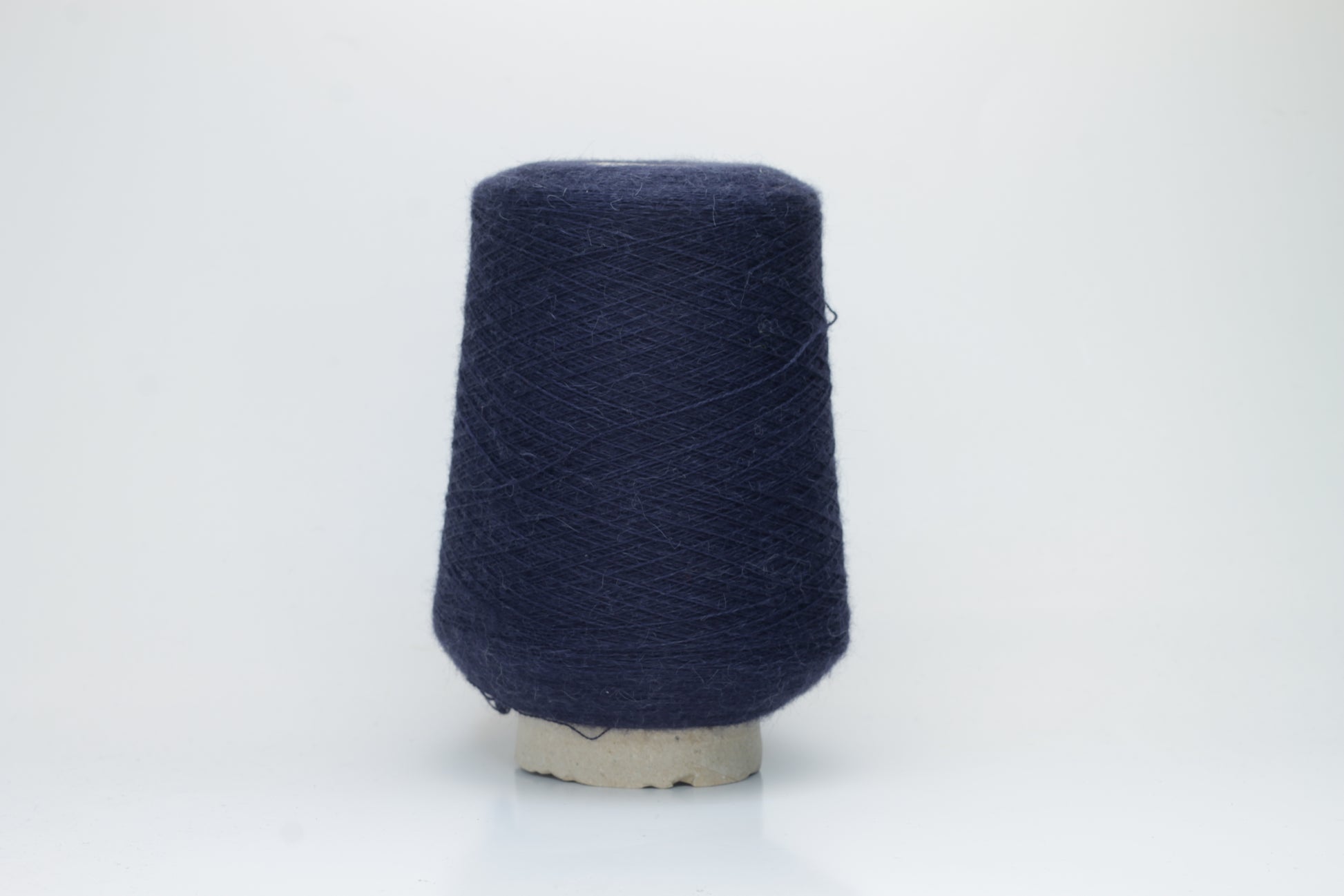 Close-up of Quipa Nm 2/28 Alpaca Merino yarn, showing its soft, slightly diffused fibers and a tight, even two-ply twist in a rich, dark navy hue.