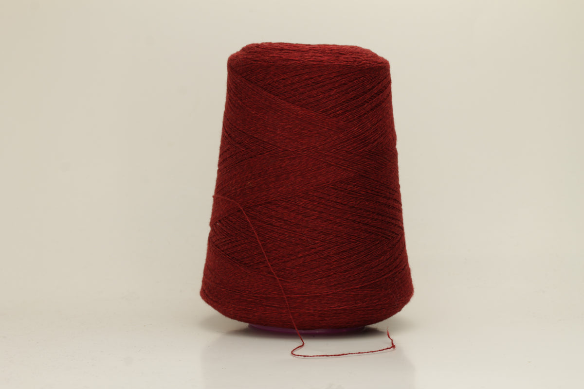 Close-up of fine 2-ply pure cashmere yarn in a rich, velvety burgundy red with subtle rosy undertones, showing its soft sheen and delicate fluff.