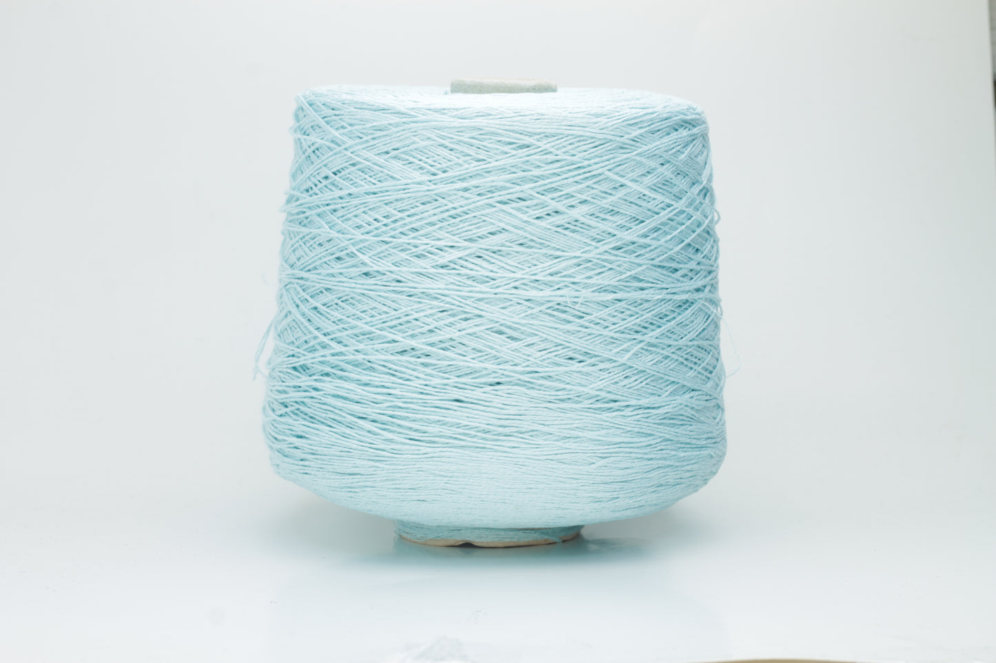 Close-up of fine, natural Linuzzo-colored 100% linen yarn, showing its smooth, slightly matte texture and subtle ply twist, coiled loosely.