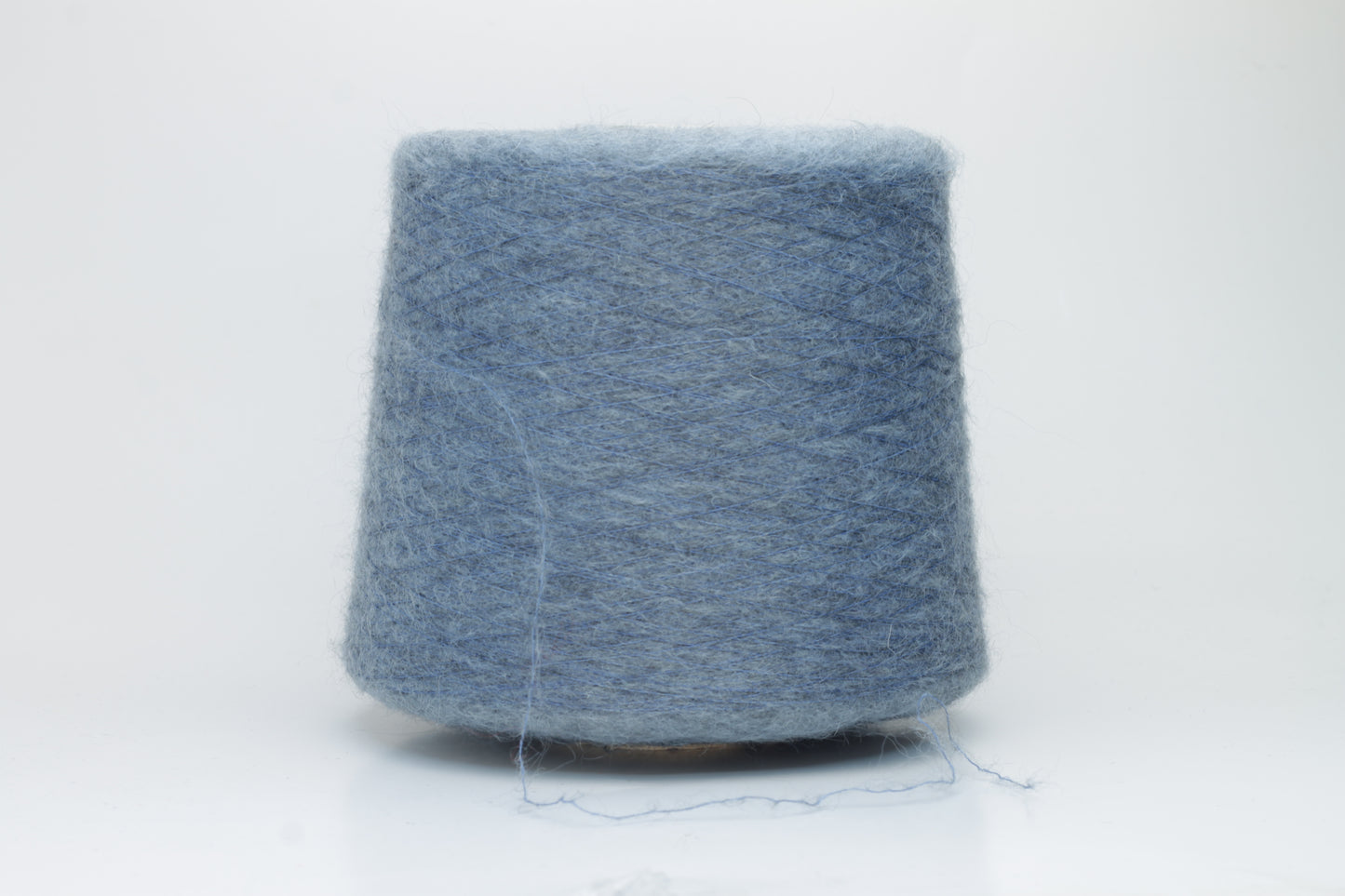 Close-up photograph showcasing a vibrant blue SuperKidMohair yarn skein, displaying a dense, fluffy texture with subtle sheen. The ply twist is evident, revealing a tightly wound thread structure.