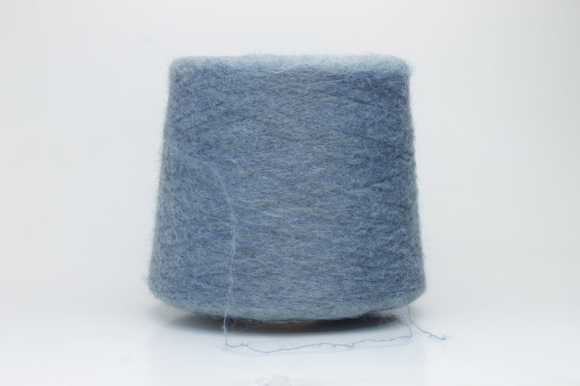 Close-up photograph showcasing a vibrant blue SuperKidMohair yarn skein, displaying a dense, fluffy texture with subtle sheen. The ply twist is evident, revealing a tightly wound thread structure.