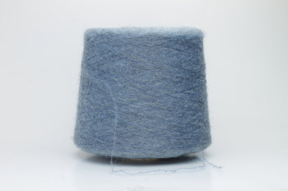 Close-up photograph showcasing a vibrant blue SuperKidMohair yarn skein, displaying a dense, fluffy texture with subtle sheen. The ply twist is evident, revealing a tightly wound thread structure.