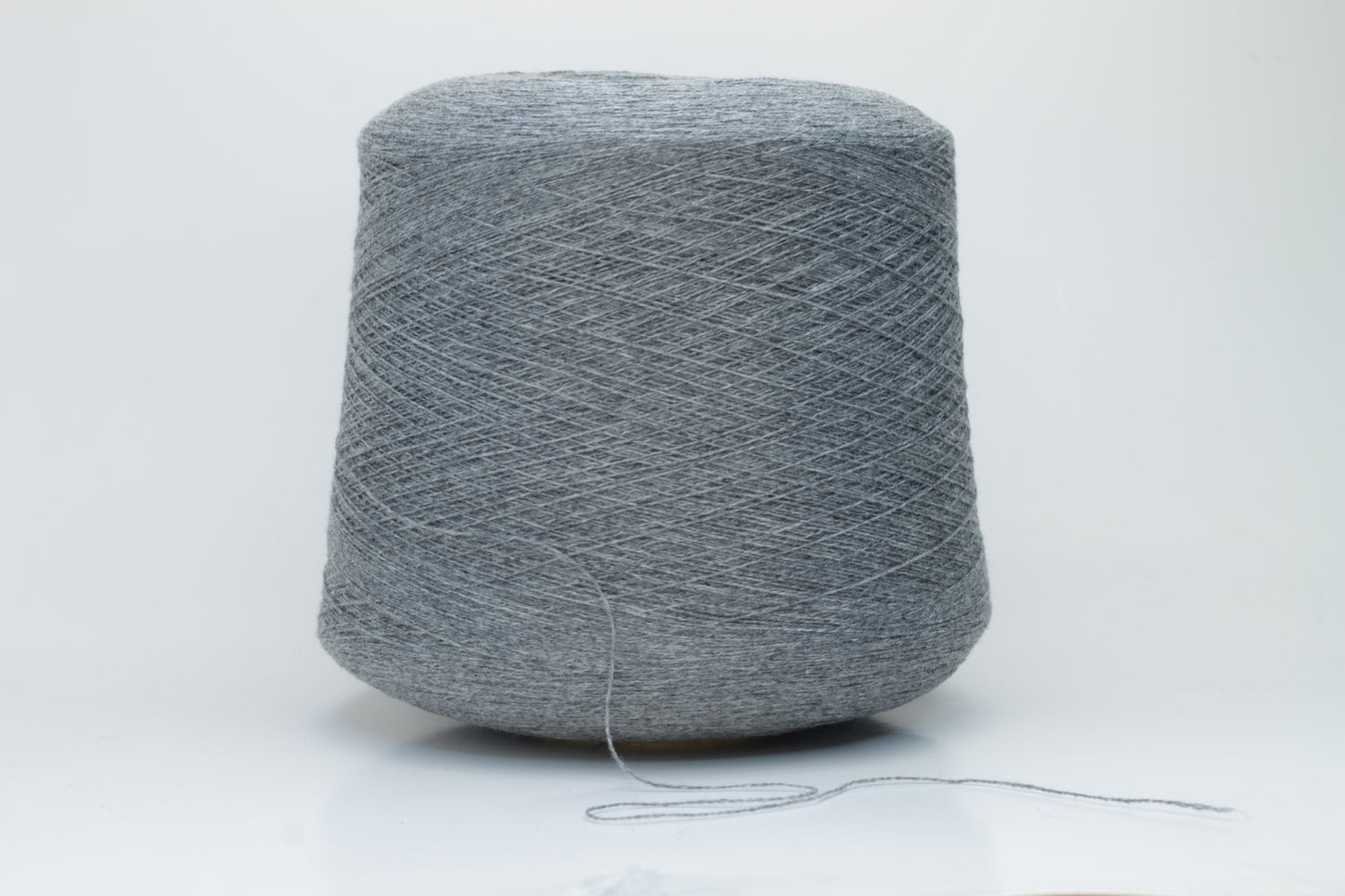 Skein of fine, two-ply cashmere yarn in a sophisticated medium gray, exhibiting a soft, subtle halo and delicate matte sheen.