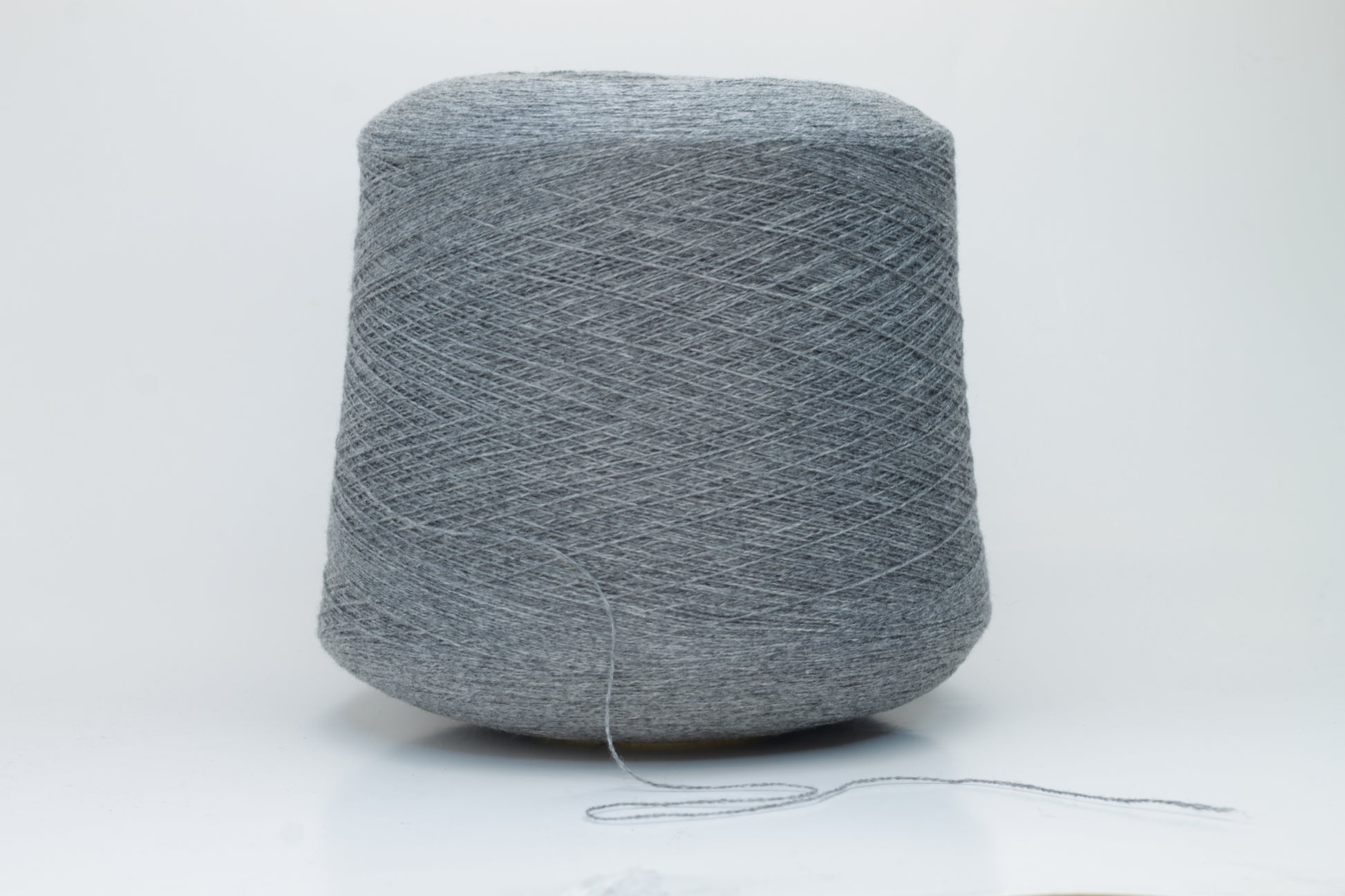Skein of fine, two-ply cashmere yarn in a sophisticated medium gray, exhibiting a soft, subtle halo and delicate matte sheen.