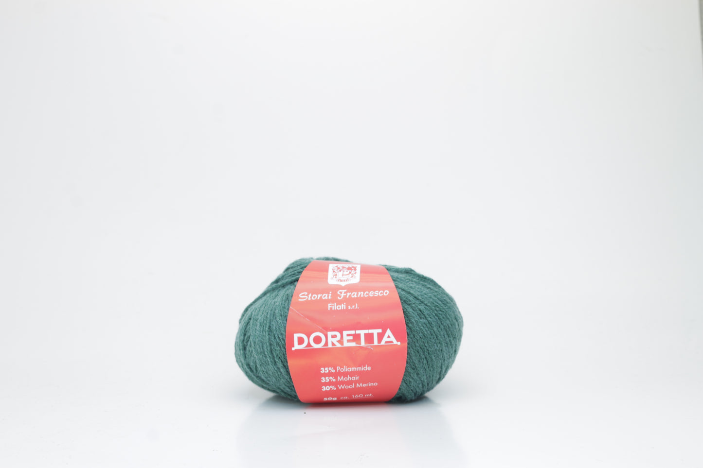 Close-up of a ball of fluffy, vibrant forest green yarn with a visible soft halo, highlighting the luxurious mohair and merino fibers.