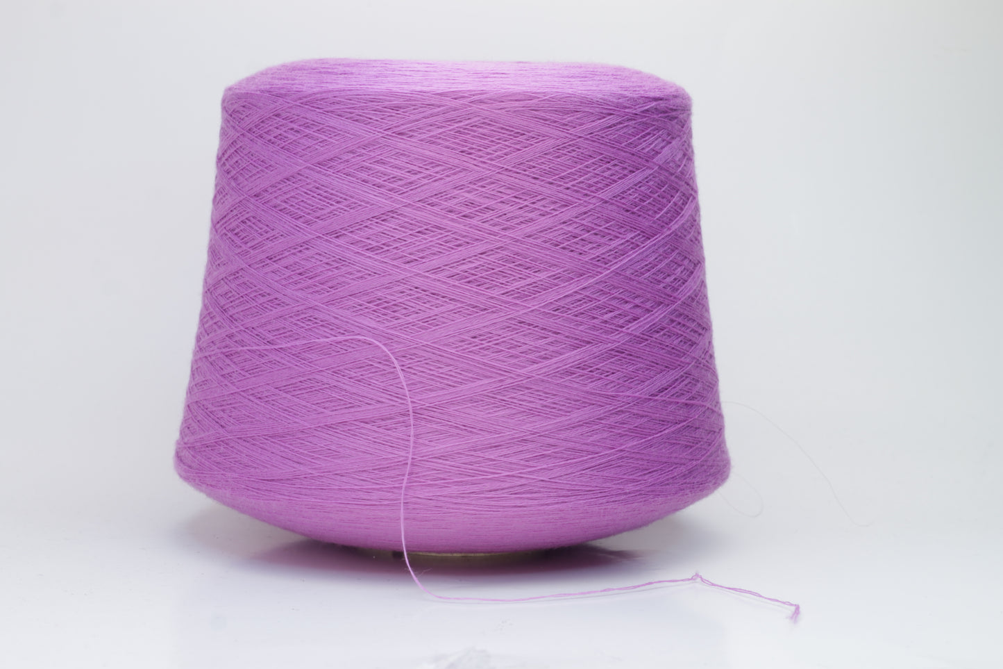 Close-up image showcasing a vibrant purple 100% merino yarn skein with a slight twist, revealing the fine ply structure and rich color depth; the fiber appears fluffy and soft.