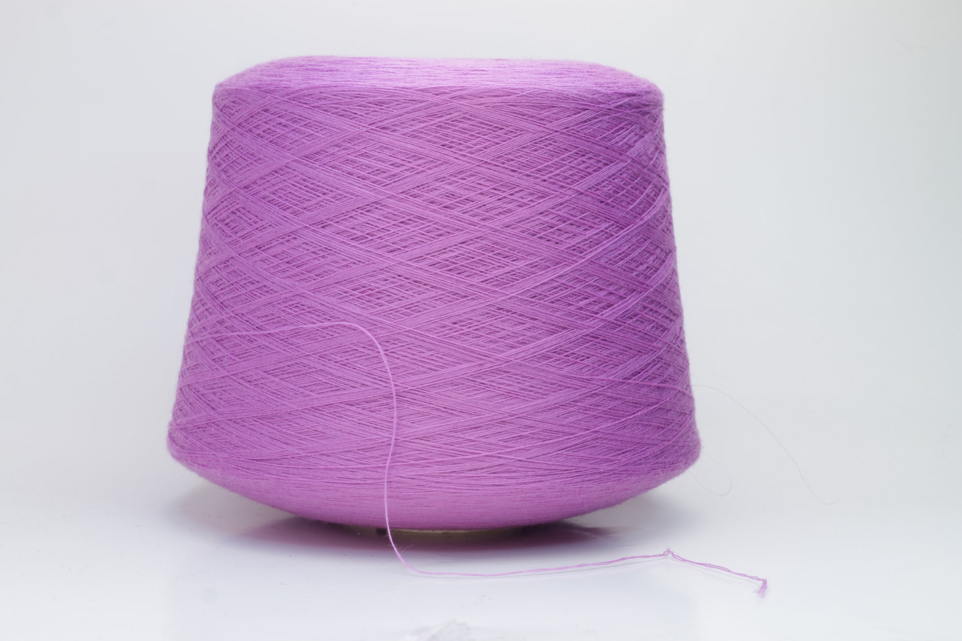 Close-up image showcasing a vibrant purple 100% merino yarn skein with a slight twist, revealing the fine ply structure and rich color depth; the fiber appears fluffy and soft.