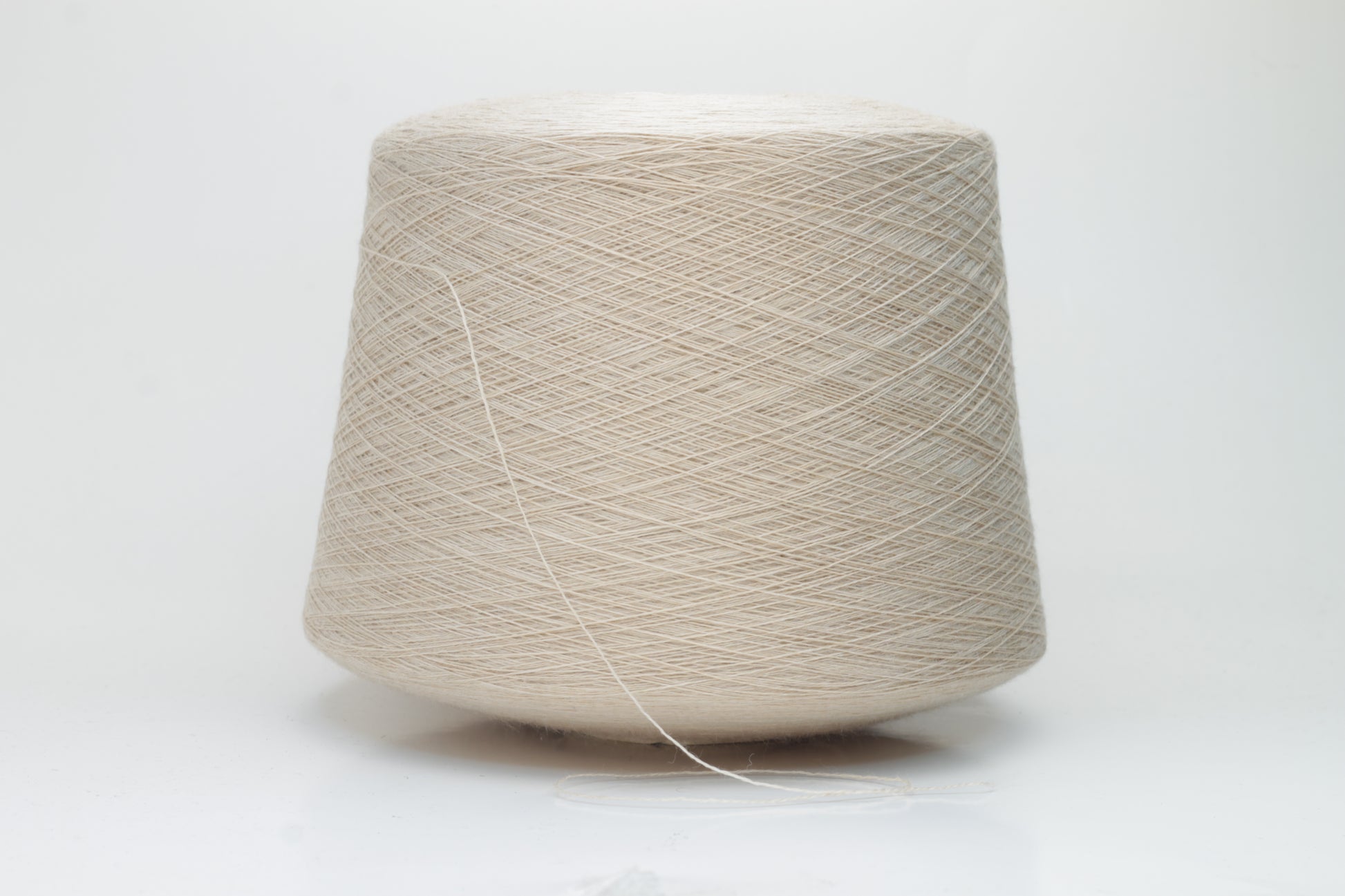 Close-up shot of creamy beige merino yarn, featuring a tight ply twist and a subtle sheen. The fibers exhibit exceptional fluffiness and texture, ideal for intricate knitting patterns.