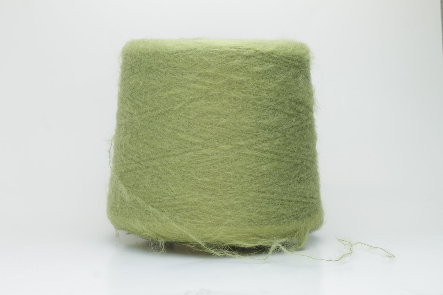 Close-up shot of vibrant green SuperKidMohair yarn showcasing a tight ply twist and rich fiber structure, revealing its inherent fluffiness and subtle sheen.