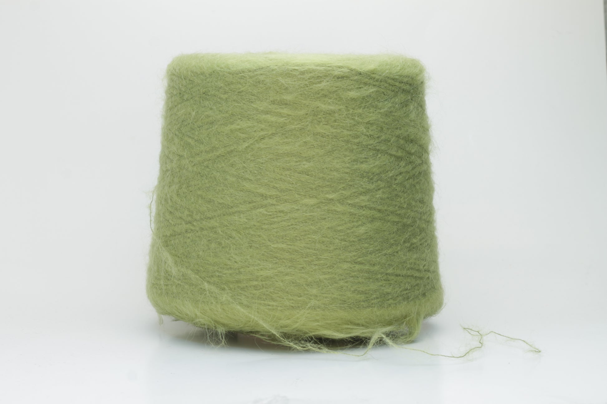 Close-up shot of vibrant green SuperKidMohair yarn showcasing a tight ply twist and rich fiber structure, revealing its inherent fluffiness and subtle sheen.