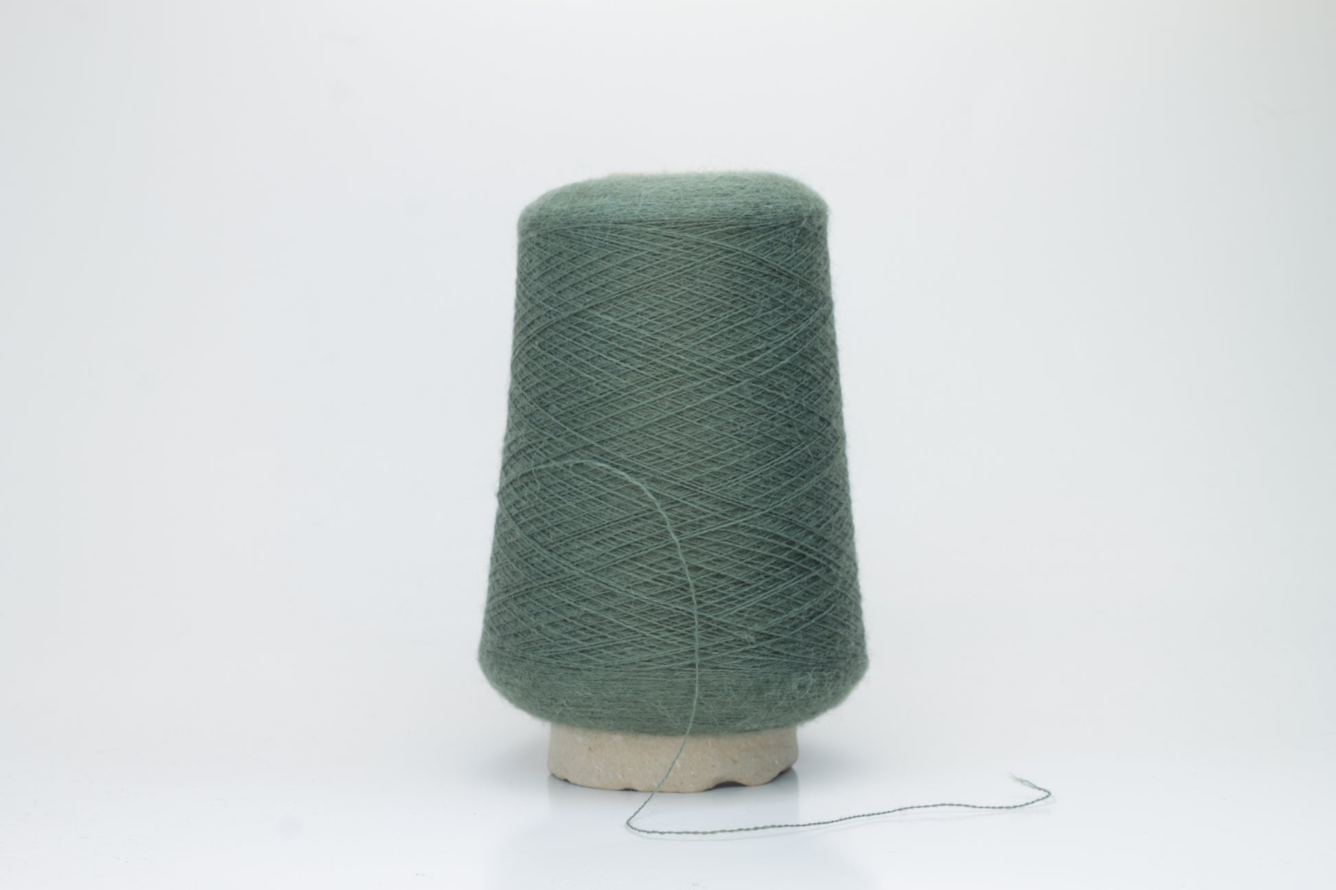 Close-up of a skein of soft, plied alpaca merino yarn in a deep green, showing subtle sheen and fine fiber halo.