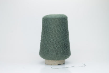 Close-up of a skein of soft, plied alpaca merino yarn in a deep green, showing subtle sheen and fine fiber halo.