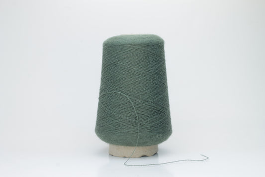 Close-up of a skein of soft, plied alpaca merino yarn in a deep green, showing subtle sheen and fine fiber halo.