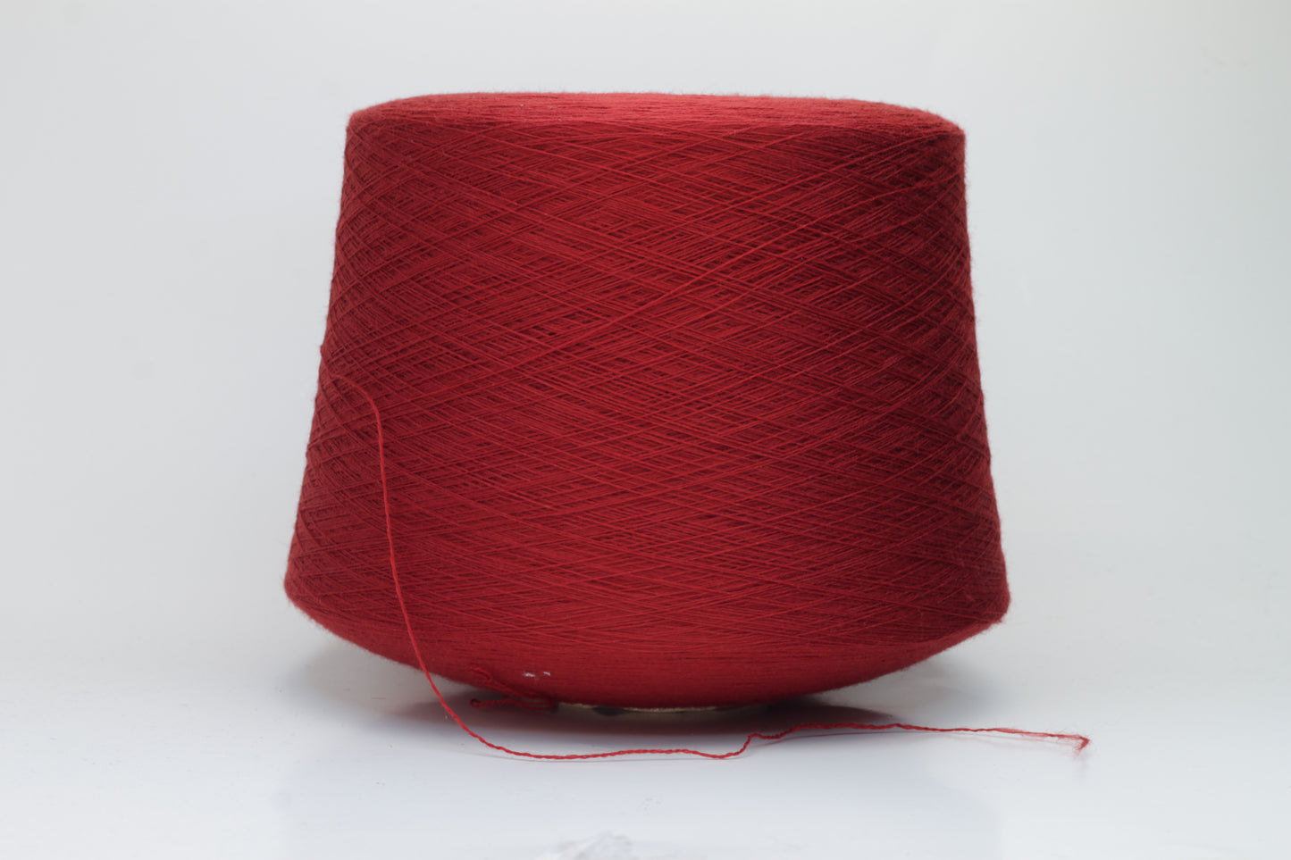 Close-up image of a vibrant red merino wool yarn skein, showcasing the smooth ply twist and subtle sheen reflecting light, with a fluffy texture.
