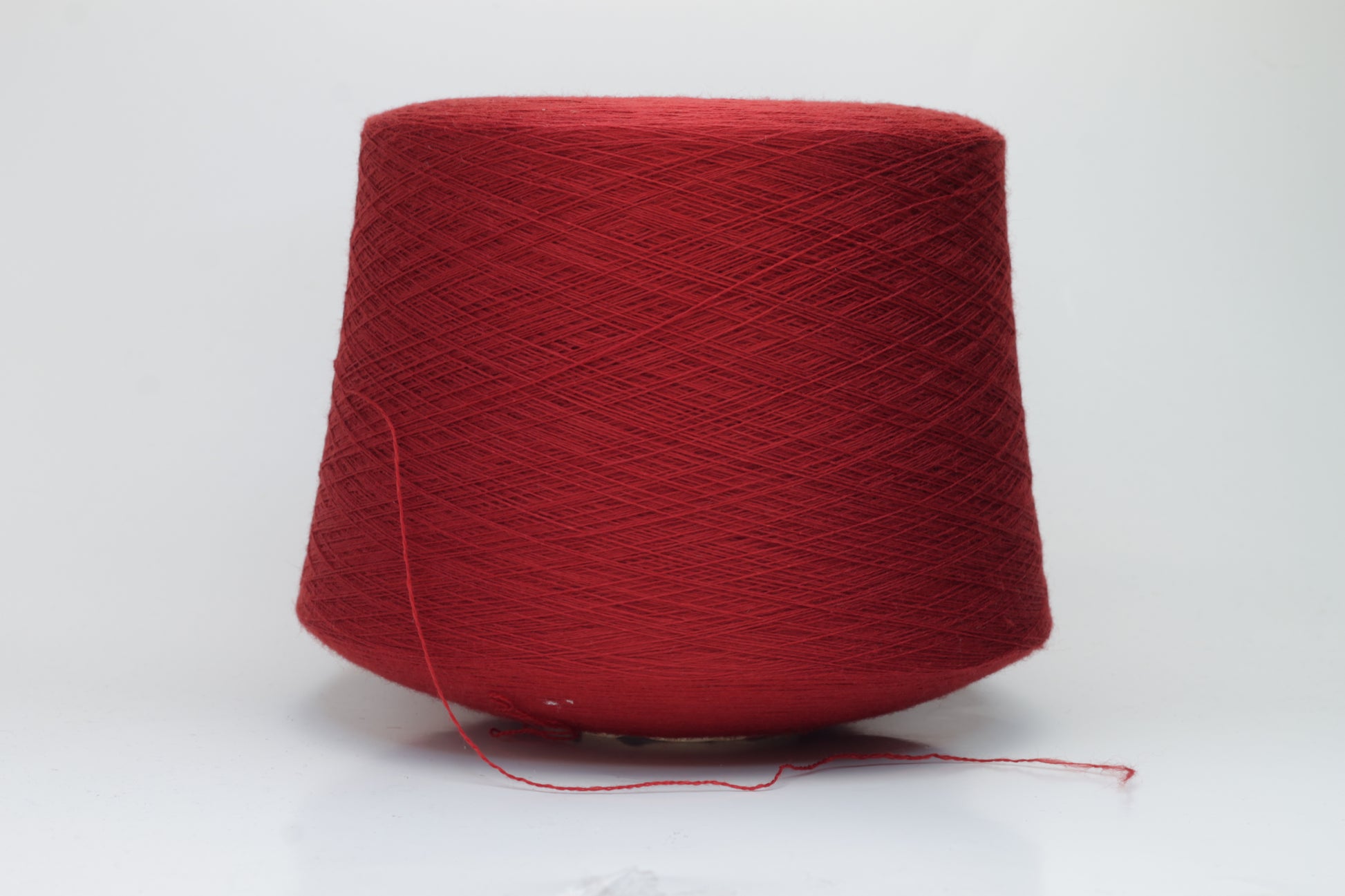 Close-up image of a vibrant red merino wool yarn skein, showcasing the smooth ply twist and subtle sheen reflecting light, with a fluffy texture.
