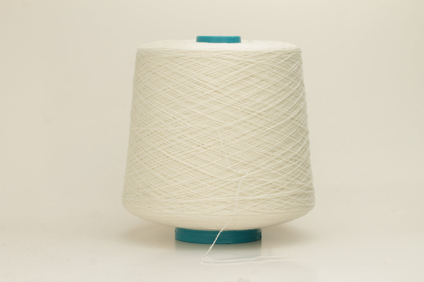 Close-up of a two-ply fine cashmere yarn, tightly twisted with a subtle matte sheen in a creamy off-white Gesso color.
