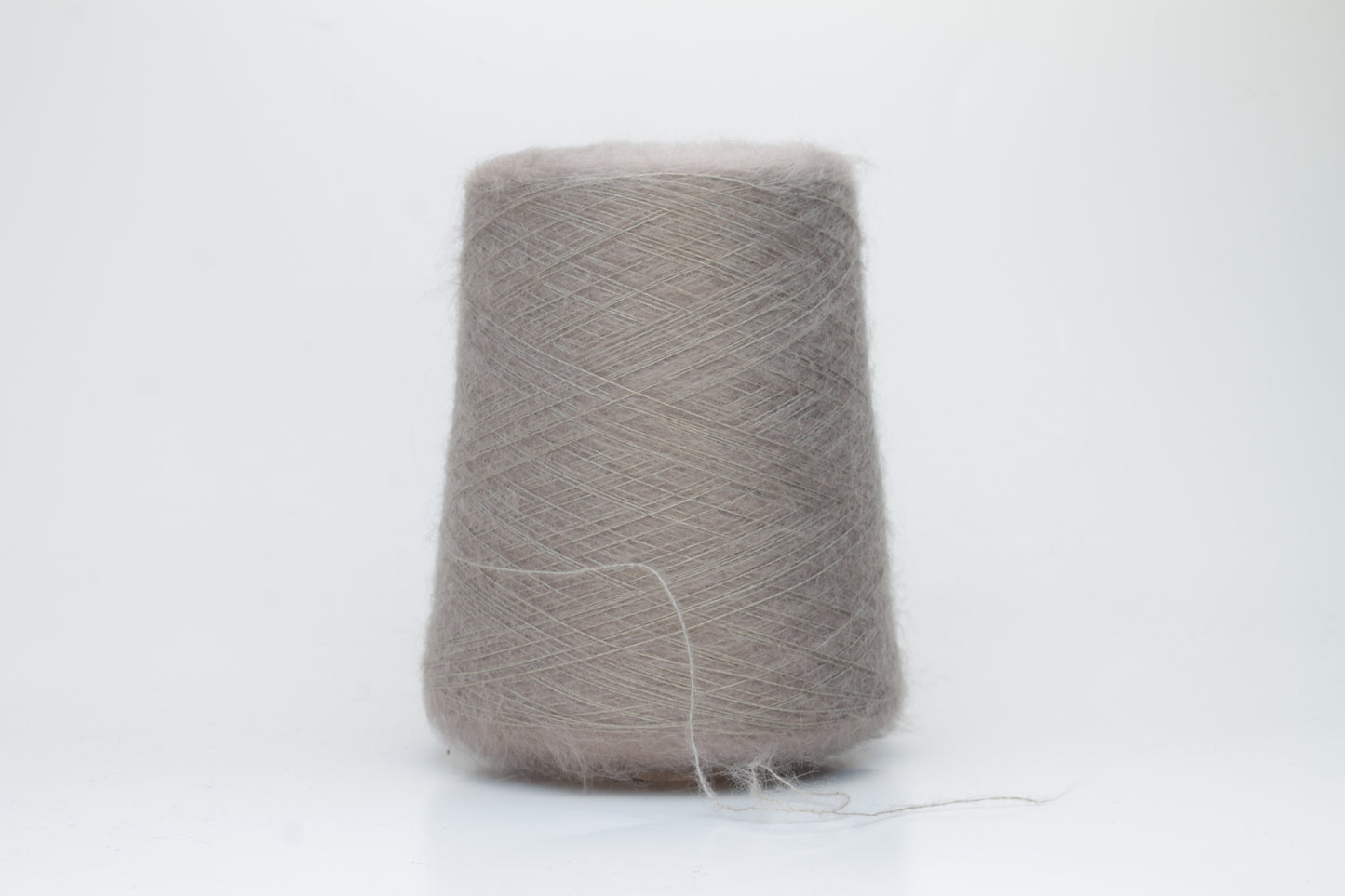 Close-up of fluffy Beige kid mohair and silk blend yarn, subtly lustrous with a soft halo, gently twisted into a fine, delicate thread.